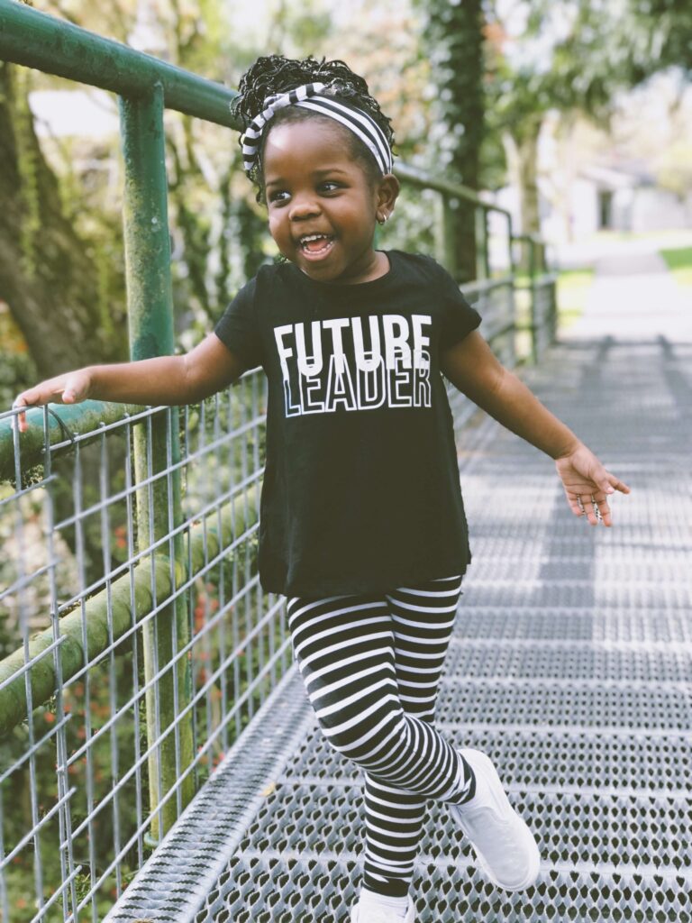 Toddler dressed in black and whit eon a bridge wearing a shirt that says Future Leader