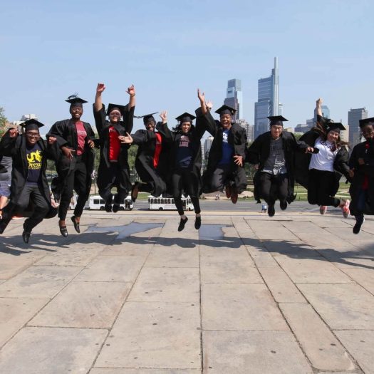 Eleven students jumping simultaneously in a line to show their happiness at graduating